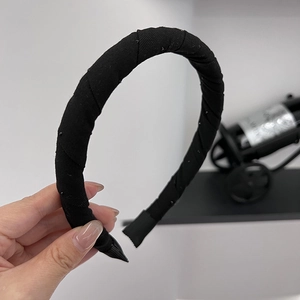Minimalist black fabric headband with subtle rhinestones shown in hand display