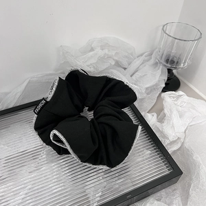 Dettaglio dell'elastico a pieghe nero con piping argento e etichetta fashion su vassoio