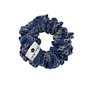 Navy blue denim scrunchie with white flower embroidery and woven fabric tag