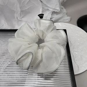 Detailed close-up of white organza scrunchie with silver edges and Fashion label