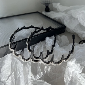 Détail d'un serre-tête à pointes avec perles blanches sur monture noire en décor artistique
