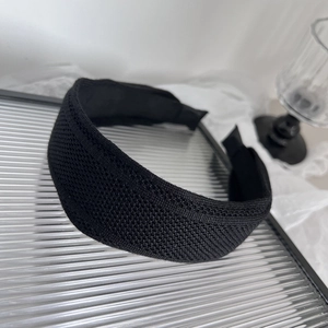 Eleganter breiter schwarzer Strickstirnband mit Netzstruktur auf Glasoberfläche