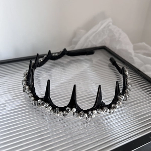 Detailed close-up of punk style black spiked headband with pearls and grey crystal beads