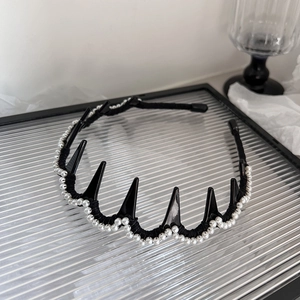 Détail d'un serre-tête punk noir avec des pointes et d'élégantes perles blanches