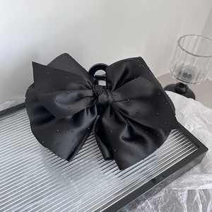 Détail d'une grande pince à cheveux en satin noir avec de délicats ornements perlés