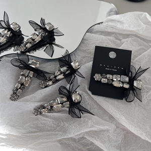 Elegant black mesh bow hair clip with sparkling crystals on mirror background