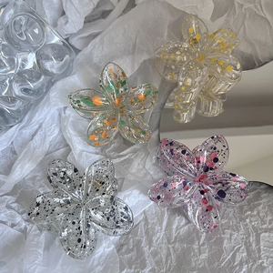Detailed macro of translucent resin frangipani hair claw clips with splatter ink design