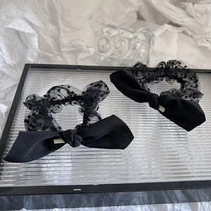 Detail of black lace hair ties with polka dot mesh bows and satin texture on glass tray
