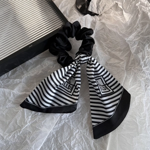 Detail of black satin hair scrunchie with long striped ribbon bow and LLDI logo