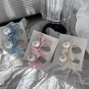 Detail view of elegant bow hair clips with pearls in blue, pink and creamy white tones