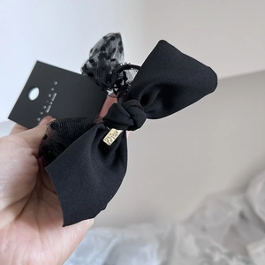 Elegant black lace bow hair tie with mesh polka dots and gold metallic detail on card