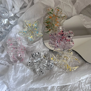 Colorful floral frangipani hair claw clips with splatter paint pattern on white paper