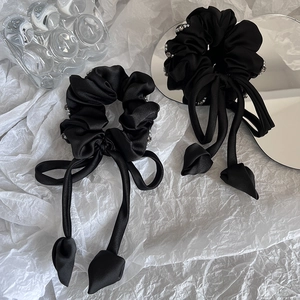 Chouchous élégants en satin noir avec longs rubans et perles sur fond blanc épuré