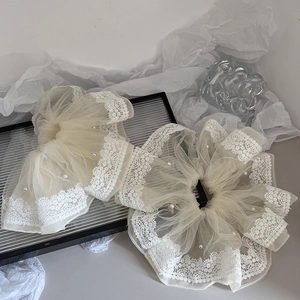 Detailed macro view of lace trim and faux pearls on cream-colored organza scrunchies