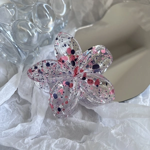 Detailed macro view of acrylic flower hair claw with pink and purple ink splatter finish
