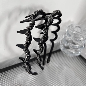 Detail of two black crystal headbands with tooth combs on a textured glass tray