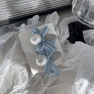 Detail of misty blue bow hairpins with large pearls on white textured card