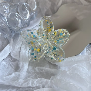Detail showing plumeria hair claw clip with blue and yellow splattered paint pattern