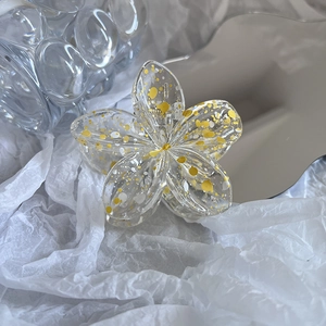 Detailed view of yellow and white splattered plumeria flower claw clip with metal spring