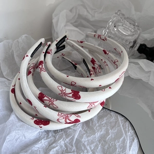 Detail of white fabric headbands with red cherry print and handmade woven label