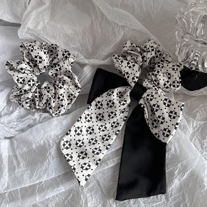 Detail of silk satin floral bow hair tie with elegant black and white pattern