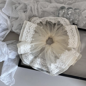 Close-up of oversized lace scrunchie with pearls on a silver tray with mesh detail