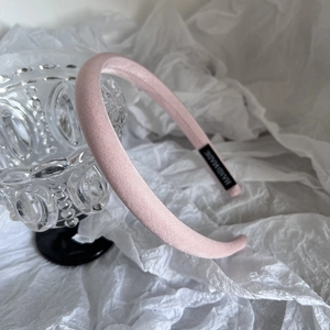 Détail d'un serre-tête en satin rose fait main avec étiquette tissée et texture soie