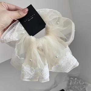 Detail of cream lace hair scrunchie featuring delicate mesh fabric and white pearl beads