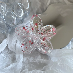 Detailed view of translucent plumeria flower hair claw with artistic colorful paint splatters