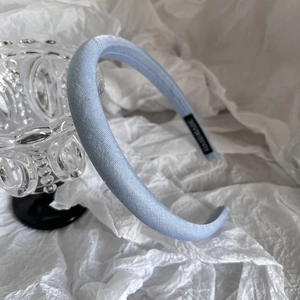 Détail d'un serre-tête rembourré en satin bleu clair fait main avec étiquette de marque