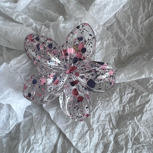Detail view of transparent plumeria flower hair claw with pink and purple dots decor
