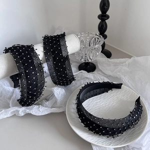 Dettaglio dell'elegante cerchietto in rete nera con strass argentati su tessuto bianco