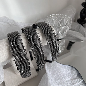 Detailed view of three luxury black rhinestone headbands displayed on white velvet stands