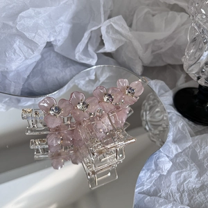 Gros plan détaillé de fleurs en résine rose et cristaux sur une pince à cheveux transparente