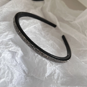 Detail view of thin rhinestone headband with non-slip teeth on white textured paper