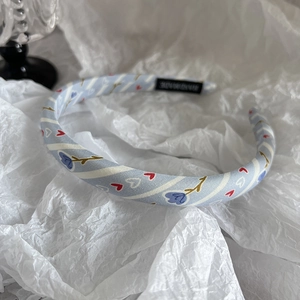 Vue détaillée d'un serre-tête bleu à motifs floraux avec étiquette faite à la main