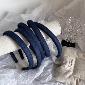 Set of 5 minimalist dark blue denim headbands on a display stand with denim fabric texture