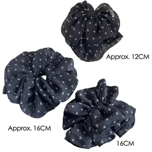 Set of black chiffon scrunchies with white heart patterns in three assorted sizes