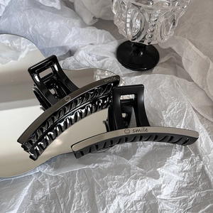 Détail macro de pinces à cheveux noires brillantes avec lettres smile et fini argenté