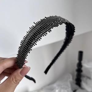 Elegant black padded headband with shimmering rhinestones and textured toothed edges