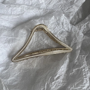 Detailed view of a gold-toned triangular hair claw clip adorned with small pearls