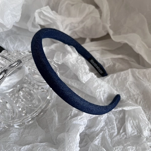 Detailed shot of dark blue denim headband featuring a white HAND MADE interior label
