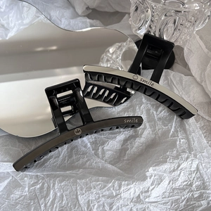 Détail de deux pinces à cheveux noires avec inscription smile argentée sur fond blanc