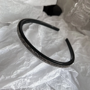 Detailed close-up of a slim black headband with sparkling rhinestones and non-slip inner teeth