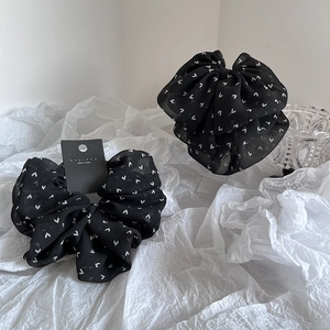Chiffon scrunchies with white heart patterns shown on a minimalist textured paper background