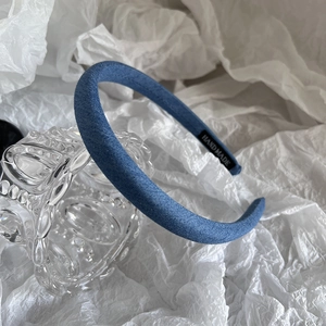 Detail view of denim fabric headband showing the handmade label and textured blue fabric