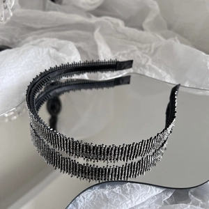 Close-up of black rhinestone headband with non-slip teeth on a reflective surface