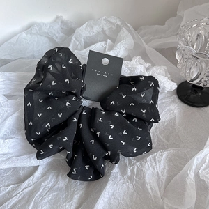 Elegant black chiffon scrunchie with white pixel heart patterns and branded tag