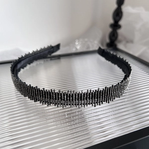Elegant black headband with shimmering silver rhinestones on a textured glass tray