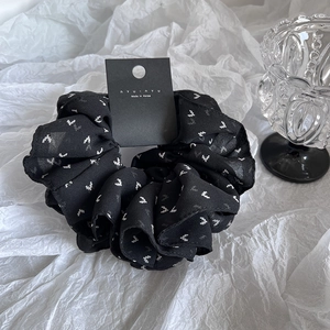 Detail of black chiffon scrunchie with white heart print and authentic brand tag